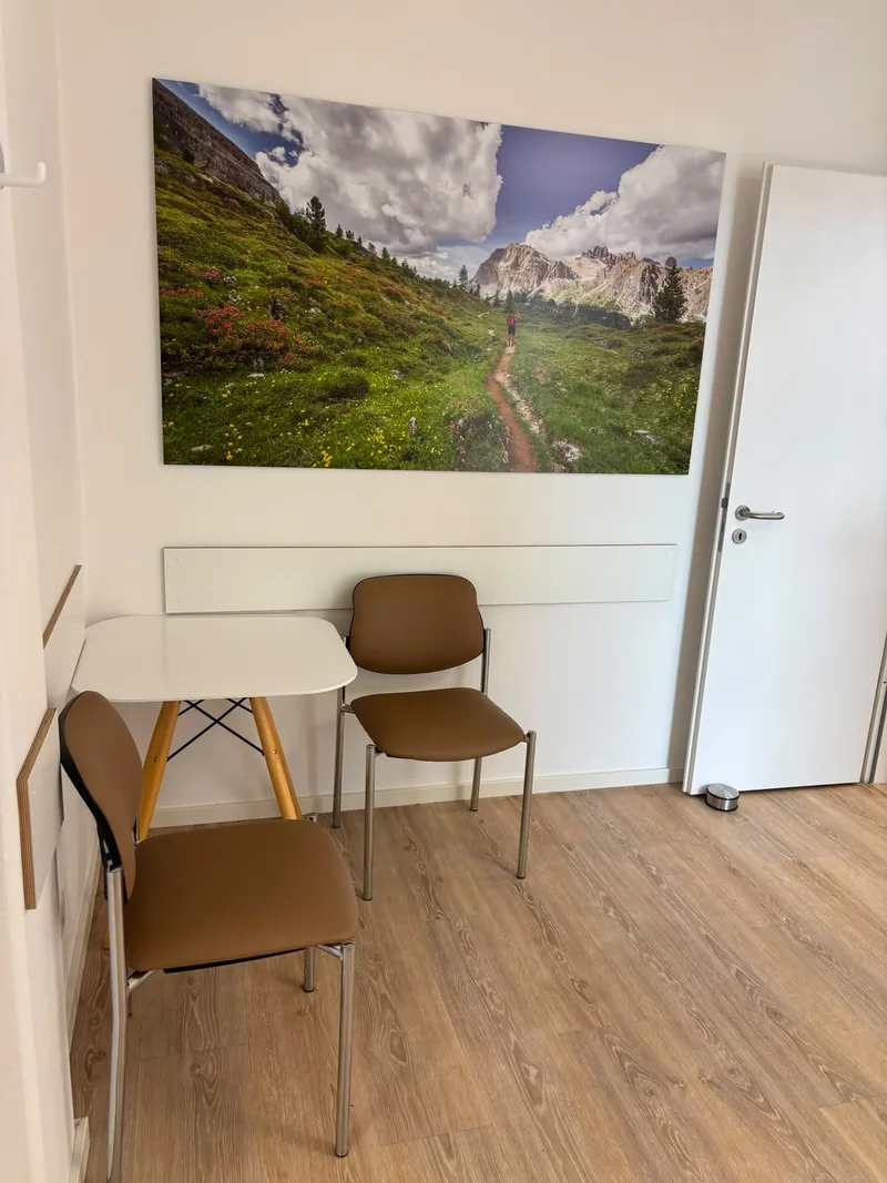 Sitzecke mit zwei Stühlen und Tisch unter einem großformatigen Landschaftsbild